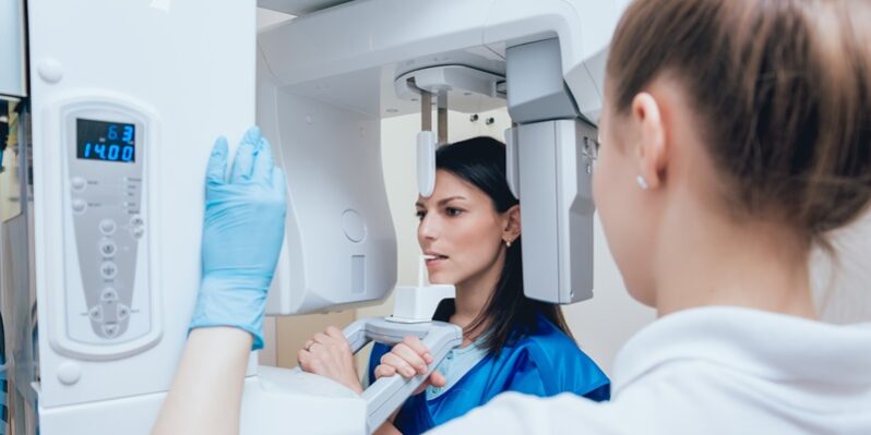 Young woman patient standing in x-ray machine.